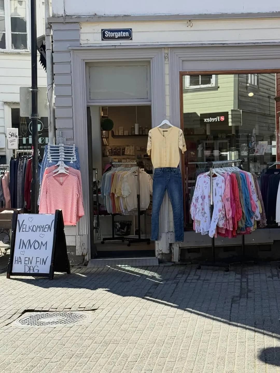 Fasaden til Toves Garn & Brukskunst i Storgaten i Egersund, med klær på stativ og velkomstskilt utenfor